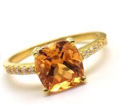 an orange and white diamond ring set in yellow gold with diamonds on the sides,