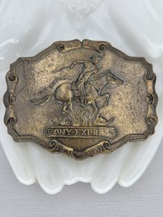 Gold tone Pony Express belt buckle. Pre-owned, vintage condition, visible wear. 3-7/8" wide x 2-7/8" tall Vintage Silver Belt Buckles For Western-themed Events, Vintage Brass Buckle Belt Buckles Collectible, Vintage Gold Belt Buckles For Collectors, Gold Antique Buckle Vintage Belt Buckles, Vintage Gold Belt Buckle With Antique Detail, Gold Antique Buckle Vintage Belt Buckle, Gold Antique Buckle Vintage Belt, Gold Vintage Belt Buckle With Antique Detail, Vintage Concho Belt Buckles