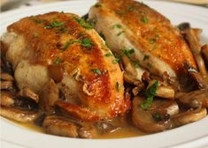 two pieces of chicken with mushrooms on a white plate