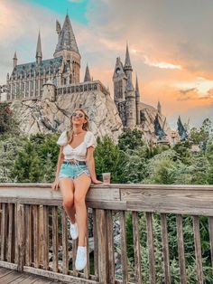 a woman sitting on top of a wooden deck next to a castle in the background