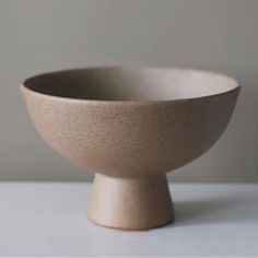 a white bowl sitting on top of a table next to a wall in the background