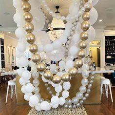 a table topped with lots of white and gold balloons