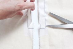 someone is cutting fabric with scissors on a tablecloth that's being sewn