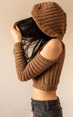 a woman wearing a brown knitted hat covering her face with her hands and hair