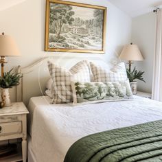 a bedroom with a bed and two lamps on either side of the bed, in front of a painting