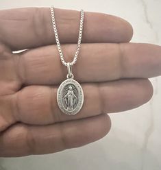 (Photo Enlarge To show Detail)✨ Discover divine elegance with our Sterling Silver Miraculous Mary Pendant. Crafted with exquisite detail, this 24mm oval pendant features an antiqued Virgin Mary, radiating timeless grace and spiritual significance. The intricately designed pendant is a symbol of faith, protection, and devotion. Made of sterling silver, it boasts enduring quality and beauty. Complete your ensemble with the optional 1.3mm box necklace, crafted from the same sterling silver for a seamless look. Whether worn for religious significance or as a fashion statement, this pendant exudes sophistication and reverence. Embrace the divine with this exquisite piece, a timeless addition to any jewelry collection. 🌟 Add the optional 1.3mm box chain for extra shine and versatility in length Elegant Oval Miraculous Medal Jewelry, Classic Oval Jewelry With Oxidized Finish, Silver Oval Pendant With Miraculous Medal, Classic Antique Silver Oval Necklace, Classic Oval Antique Silver Necklace, Oval Miraculous Medal Spiritual Jewelry, Sterling Silver Oval Necklace With Miraculous Medal, Oval Sterling Silver Necklaces With Miraculous Medal, Antique Silver Oval Jewelry With Oxidized Finish