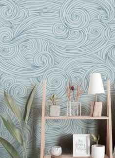 a room with a shelf, lamp and wallpaper that has waves painted on it