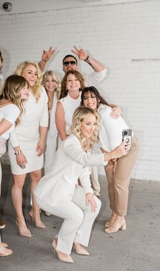 the beautiful women in white dresses posing for a group photo with one woman's legs crossed