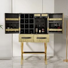 an open cabinet with wine bottles in it on a marble floor next to a potted plant