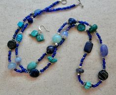 This 36 inch necklace is made from small dark blue beads with other larger beads in turquoise, light blue, and dark blue.  There are also silver accent beads.  It has a small toggle clasp.  The matching earrings are included.  This long necklace will look great with blues, white, black and beige.  It is very versatile. Purple Jasper, Heishi Necklace, Hematite Necklace, Blue Stones, Seed Bead Necklace, Magnetic Bracelet, Light Turquoise, Green Turquoise, Silver Accents