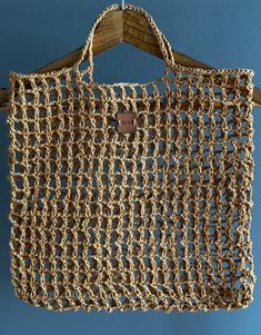 a bag hanging on a wooden hanger with a blue wall in the back ground