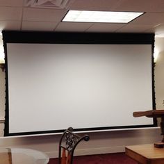 an empty room with a projector screen on the wall