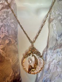 Just a beautiful bronze detailed mermaid swimming her scallop sea shell among her "bubble" faux pearls of different sizes. The Art Nouveau style bronze mermaid is inside a real raw painted gold sea shell (clam shell NOT oyster) with your choice of a faux pearl (26") or matching light bronze chains (20"). Both necklace are adjustable long or short. This is such a cool piece that's natural wearable art. The seashell is about 1.5" x 2."  Mermaids have been associated with many ancient myths and leg Gold Brass Fantasy Necklaces, Gold Fantasy Brass Necklaces, Gold Fantasy Necklace In Metal, Fantasy Gold Brass Necklaces, Ocean-inspired Gold Jewelry For Party, Vintage Shell Gold Jewelry, Vintage Gold Beach Jewelry, Vintage Gold Jewelry For Beach, Vintage Gold Necklace For Beach