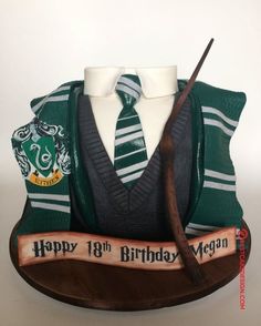 a harry potter birthday cake with a wand and tie on it's display stand