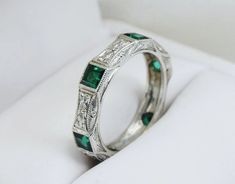 an emerald and diamond ring sits in a box