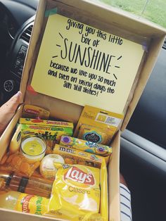 someone is holding up a box of sunshine and other items in their car's dashboard