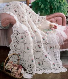 a white crocheted blanket sitting on top of a pink chair next to a potted plant