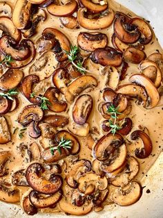 a pizza topped with mushrooms and herbs on top of a pan