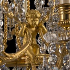 a golden chandelier with crystal beads hanging from it's sides and an angel figurine on top