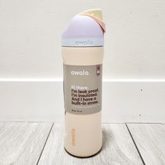 a bottle that is sitting on the floor next to a white wall and wood floor