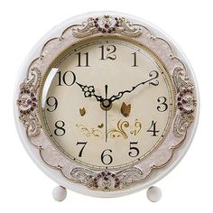 an ornate white clock with gold trimmings and numbers on the face, set against a white background