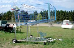 a metal cage on wheels with cows in the background