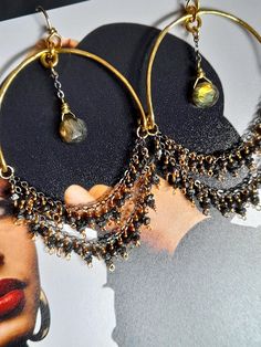 These gorgeous hoop earrings showcase hand formed and hammered moon shape frame bottomed with golden flash Labradorite drops and a gold filled chain embellished with little sparkly rough black Diamonds, all meticulously wired with a gold filled wire to make an unique round hoops, hanging on hand-formed brass ear wire. This pair of earrings is lightweight but very eye catching and one-of-a-kind. The earrings measure 3.1 inches (8cm) from the top of the ear wire to the bottom of the Diamond beads. The frame's width is approx. 1.6 inches (4cm). Black Diamond Hoop Earrings, Moon Shape, Black Diamonds, Bohemian Earrings, Diamond Hoop Earrings, Gold Hoops, Precious Gemstones, Gold Filled Chain, Ear Wire