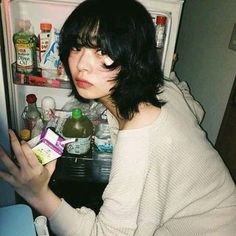 a woman is looking in the refrigerator with her hand on an empty carton box