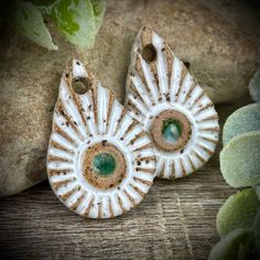 two white and green earrings sitting next to each other on top of a wooden table