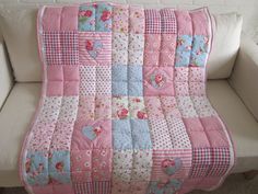 a white couch with a pink and blue patchwork quilt on it's back