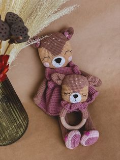 two teddy bears sitting next to each other near a vase with some flowers in it