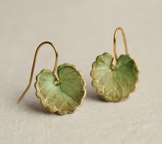 These olive green leaf earrings are brass charms with some amazing detail, which have been carefully treated, painted and varnished to bring out beautiful tones and depth of colour and to show the incredible veining and other details of the metal.  These are coloured a beautiful, delicate and multi toned olive green colour.   They are designed to be reminiscent of the beautiful, softly coloured lily pads found in Art Nouveau paintings. They are handmade in our Edinburgh studio and no two pairs are quite the same!  Our Leaf Earrings are available in two finishes: soft matte or a shiny glass appearance. The colour and level of detail on the earrings are exactly the same regardless of which you choose.  We've included an image for a better idea.   Each leaf is 15mm long. We offer these leaf e Handmade Enamel Jewelry, Lily Pad Earrings, Green Brass Earrings Nature-inspired, Nature-inspired Green Brass Jewelry, Green Brass Earrings, Green Leaf-shaped Jewelry With Matching Earrings, Green Brass Earrings As Gift, Green Brass Earrings For Gift, Accesories Outfit Jewelry