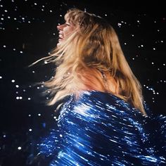 a woman with long hair standing in front of some lights and sparkles on the ground