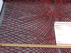 a piece of red wire mesh next to a ruler