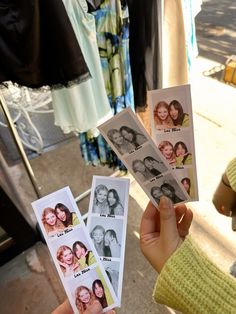 a person holding up four polaroid photos with their faces on them in front of clothing racks