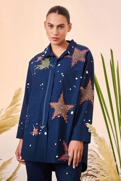 Navy blue oversized shirt with contrast thread and bead embroidered star motifs and patch pockets in front.
Component: 1
Pattern: Embroidered
Type Of Work: Thread and Beads
Neckline: Spread Collar
Sleeve Type: Full
Fabric: Poplin
Color: Blue
Other Details: 
High low hem shirt
Patch pockets in front
Closure: Concealed button front
Note: Pant worn by the model is not for sale
Occasion: Party - Aza Fashions Clothing Store Interior, Shirt For Women, Online Tops, Pant Set, Shirt And Pants, Straight Pants, Shirt Pattern, Oversized Shirt, Western Wear