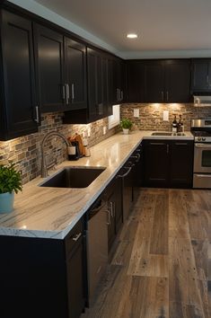 a kitchen with black cabinets and white counter tops, wood flooring and stainless steel appliances