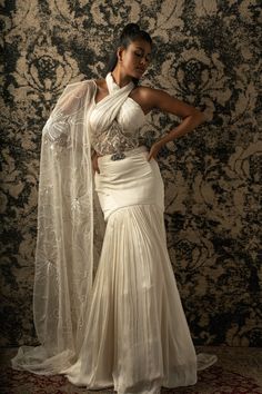 This Indian ensemble is a celebration of elegance and grace. The ivory fishcut skirt, crafted from satin silk, drapes effortlessly, while the blouse, shimmering in organza and net, adds a touch of glamour. Completing the ensemble is a flowing cape made of organza, exuding ethereal charm with every movement. Together, these pieces create a captivating and sophisticated look fit for any special occasion.From Jigar & Nikita's Summer Romance collection. DELIVERY TIMEPlease allow 8-12 weeks for your Skirt Organza, Skirt Lehenga, Bridal Crop Top, Silk Drapes, Sequin Cape, Tuxedo Accessories, Ivory Skirt, Beach Wedding Guests, Net Blouses