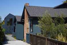 the house is blue and has a brown fence around it, along with some trees