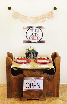 a wooden table topped with plates and cups next to a sign that says tiny torts cafe