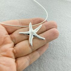 a hand holding a silver starfish pendant