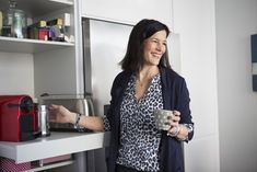 a woman is holding a cup and smiling