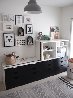 a white and black room with pictures on the wall, bookshelf and drawers