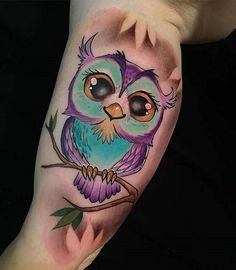 an owl with big eyes sitting on a tree branch by the artist's arm