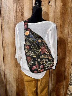 "Discover the perfect accessory for your everyday adventures with this handmade sling bag in a beautiful floral canvas, featuring a unique flower design on black canvas. This versatile bag has 3 compartments, including a handy front pocket, a middle zipper pocket, and a small inside pocket, perfect for keeping your cell phone close at hand. The bag also features an adjustable strap that can be easily customized to fit your style, with a length that adjusts from 38\" to 54\". For the perfect fit, Black Bags With Floral Print For Gifts, Everyday Black Bag With Floral Print, Black Floral Print Shoulder Bag For Everyday Use, Elegant Black Floral Print Shoulder Bag For Everyday Use, Elegant Black Floral Print Shoulder Bag, Casual Floral Print Shoulder Bag Perfect For Gift, Casual Black Backpack For Gift, Casual Backpack Perfect As A Gift, Black Floral Print Shoulder Bag