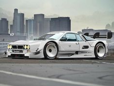 a white car parked in front of a city skyline