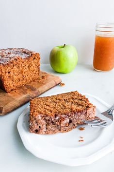 a piece of cake on a plate with a fork next to it and an apple in the background