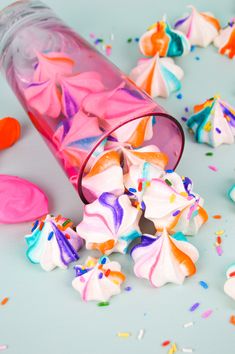 colorful candies spilling out of a bottle onto the ground with confetti scattered around