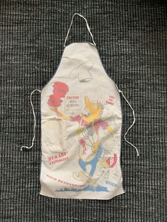 an apron that is on the ground with writing on it and cartoon characters drawn on it