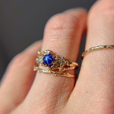 a close up of a person's hand holding a ring with a blue stone